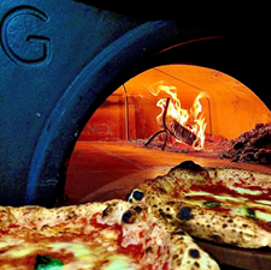 An image of a wood-fired pizza oven with two pizzas