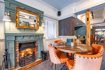 An image from inside The Woodside. A round table, for four, in front of a log fire.