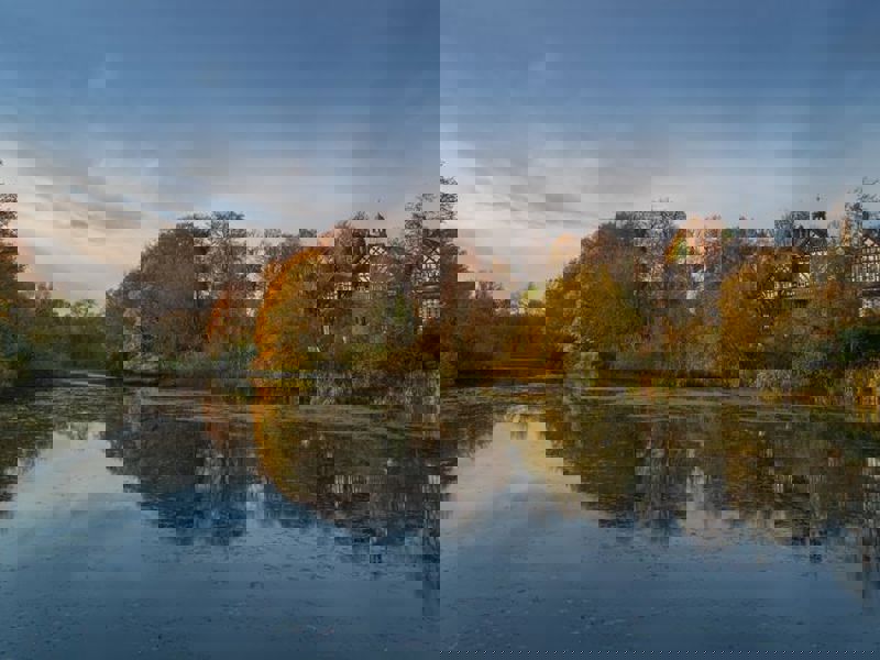 A lake with a black and white building in the background which is located in Worsley