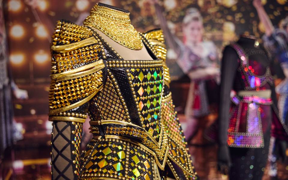 Photo of black and gold costume on mannequin with other costume displays in background